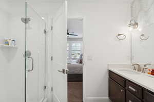 Bathroom featuring connected bathroom, vanity, a stall shower, carpet, and a ceiling fan