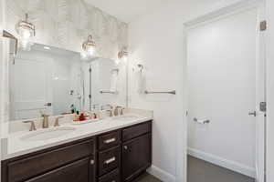 Bathroom with double vanity, a stall shower, and dark tile patterned flooring