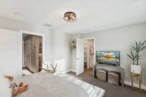 Carpeted bedroom with connected bathroom and baseboards