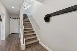 Stairs featuring wood finished floors and recessed lighting