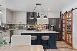 Kitchen with a kitchen bar, stainless steel appliances, tasteful backsplash, pendant lighting, and recessed lighting