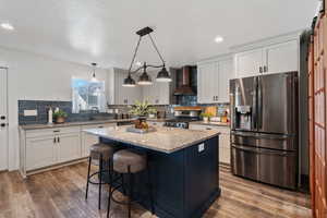 Kitchen with appliances with stainless steel finishes, light stone counters, a barn door, tasteful backsplash, and a textured ceiling