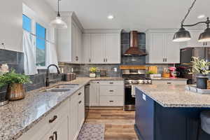 Kitchen featuring pendant lighting, light stone counters, stainless steel appliances, white cabinetry, and recessed lighting