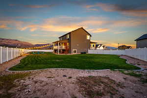 Back of house featuring a mountain view, a patio, a fenced backyard, and a balcony