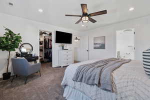 Carpeted bedroom featuring a spacious closet, a ceiling fan, and recessed lighting