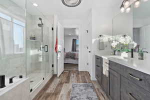 Ensuite bathroom featuring vanity, light wood-style floors, a shower stall, recessed lighting, and tiled bath