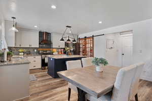 Dining room with a barn door, light wood-style floors, and recessed lighting