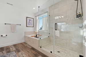 Bathroom featuring wood finished floors, a stall shower, a garden tub, and recessed lighting