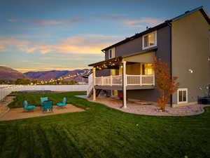 Back of property at dusk featuring stairway, a fenced backyard, a patio, stucco siding, and a deck with mountain view