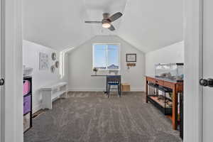 Office featuring dark colored carpet, vaulted ceiling, ceiling fan, and a textured ceiling