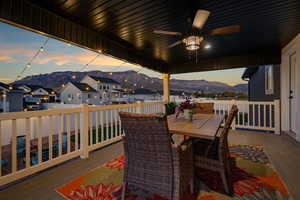 Wooden deck featuring a mountain view, outdoor dining area, and a ceiling fan