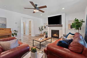 Living room featuring a fireplace, wood finished floors, ceiling fan, recessed lighting, and a textured ceiling