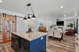 Kitchen with light stone counters, hanging light fixtures, a center island, light wood-style floors, and recessed lighting