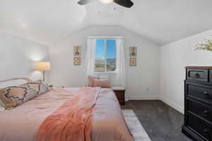 Bedroom featuring dark colored carpet, vaulted ceiling, a textured ceiling, and ceiling fan