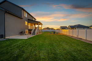 Yard at dusk with stairs, a patio, and a fenced backyard