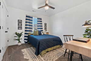 Bedroom with dark colored carpet and a ceiling fan