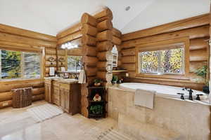 Full bathroom with double vanity, a garden tub, plenty of natural light, and high vaulted ceiling