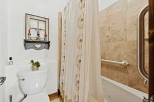 Full bathroom with toilet and a combined bath / shower with jetted tub