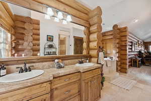 Full bath with rustic walls, double vanity, and recessed lighting