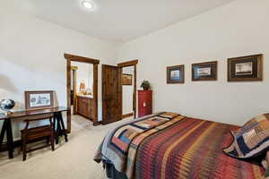 Bedroom featuring light carpet and ensuite bathroom