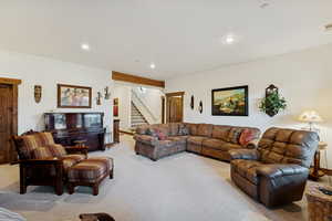 Living area with carpet floors, recessed lighting, and stairway