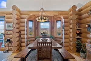 Dining space with wood-type flooring, rustic walls, a mountain view, and vaulted ceiling