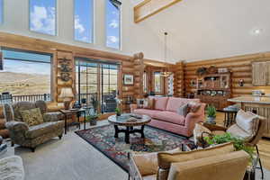 Living area featuring high vaulted ceiling, log walls, and beamed ceiling