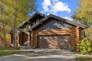 Log-style house featuring log siding, concrete driveway, and an attached garage