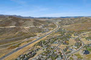 Aerial view of property and surrounding area featuring mountains and nearby suburban area