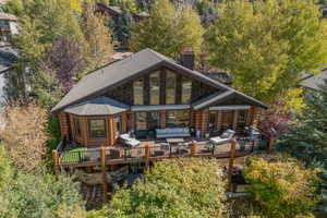 Back of house with an outdoor hangout area, log siding, a wooden deck, and view of wooded area