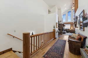 Hallway featuring high vaulted ceiling, light wood finished floors, and an upstairs landing