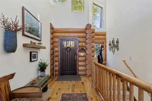 Foyer entrance featuring hardwood / wood-style flooring, a high ceiling, and log walls