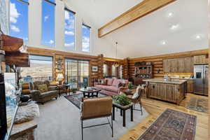 Living room with high vaulted ceiling, beam ceiling, recessed lighting, light wood-style floors, and rustic walls