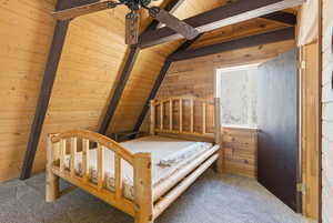 Carpeted bedroom with wooden ceiling and wooden walls