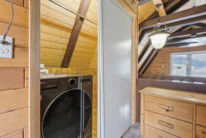 Laundry room with wood walls, washer / dryer, and wooden ceiling