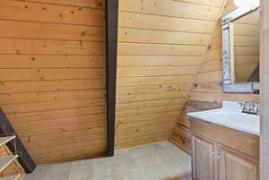 Bathroom featuring wooden walls, vanity, vaulted ceiling, and wood ceiling