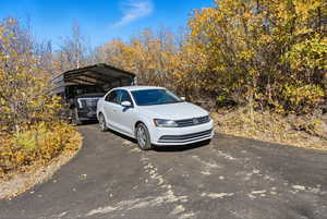View of vehicle parking featuring asphalt driveway and a detached carport