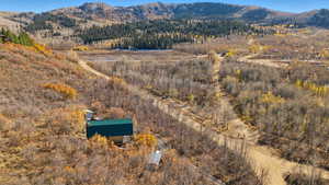 View of subject property featuring a mountain backdrop and a forest