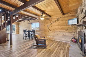 Playroom featuring wooden walls, wood finished floors, a chandelier, a ceiling fan, and a wood ceiling with exposed beams