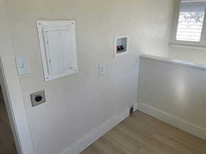 Washroom featuring electric panel, wood finished floors, hookup for a washing machine, and hookup for an electric dryer
