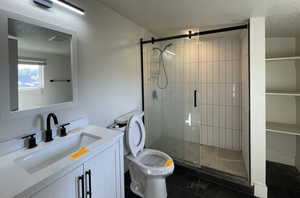 Full bath with vanity, a stall shower, dark tile patterned floors, and a textured ceiling