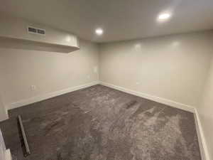 Finished below grade area with dark carpet and recessed lighting