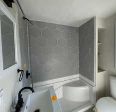 Full bath with shower / washtub combination and a textured ceiling