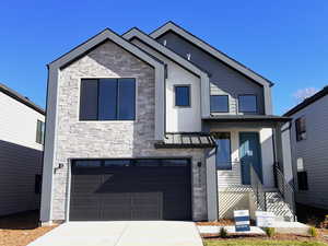 Contemporary house featuring stone siding, a garage, concrete driveway, and stucco siding