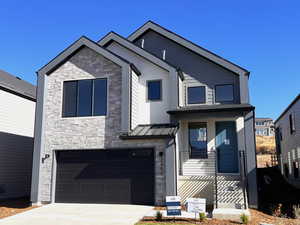 View of front of home with stone siding, an attached garage, driveway, and a metal roof