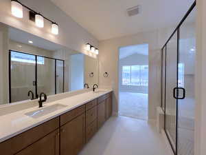 Owner's bathroom featuring double vanity, a stall shower, healthy amount of natural light, light tile patterned floors, and lofted ceiling