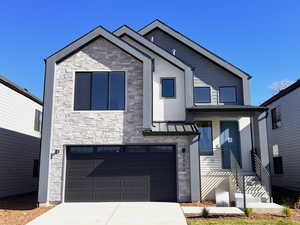 Contemporary house featuring stone siding, an attached garage, concrete driveway, and stucco siding