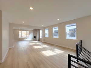 Unfurnished living room with recessed lighting, a tile fireplace, and light wood-style flooring
