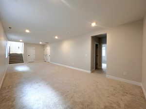 Empty room with stairway, light carpet, and recessed lighting