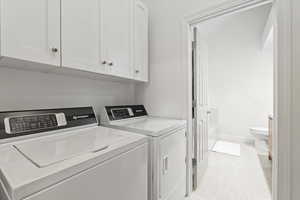 Washroom with separate washer and dryer, cabinet space, and light tile patterned floors